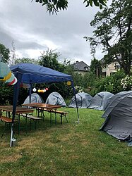 Zelte und ein Pavillon mit Tischen auf einer Rasenfläche aufgebaut.