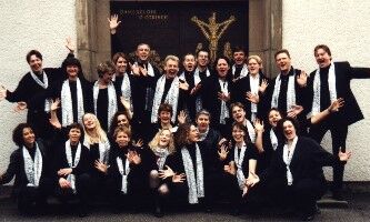 Große Chorgruppe posiert enthusiastisch in Schwarz-Weiß.