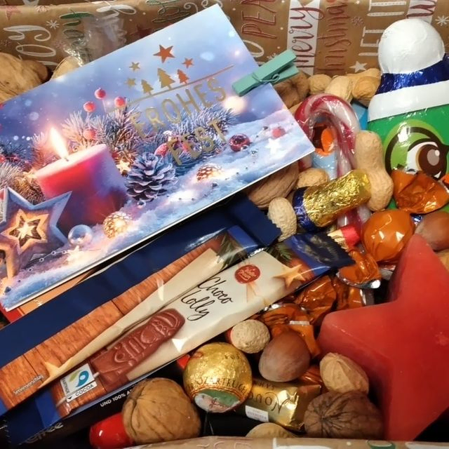 Nahaufnahme eines Geschenkkorbes mit Weihnachtsschmuck, Nüssen und Süßigkeiten.