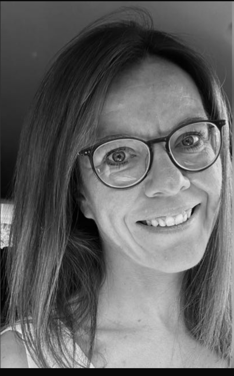 Schwarz-weißes Porträt einer lächelnden Frau mit Brille.