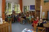 Kinder sitzen an Tischen in einem hellen Klassenzimmer.